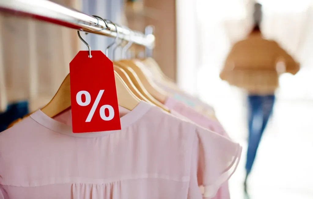 Prenda rosa en oferta cuelga junto a una etiqueta roja de descuento.