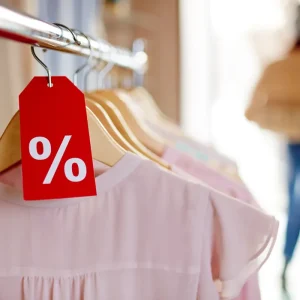 Prenda rosa en oferta cuelga junto a una etiqueta roja de descuento.